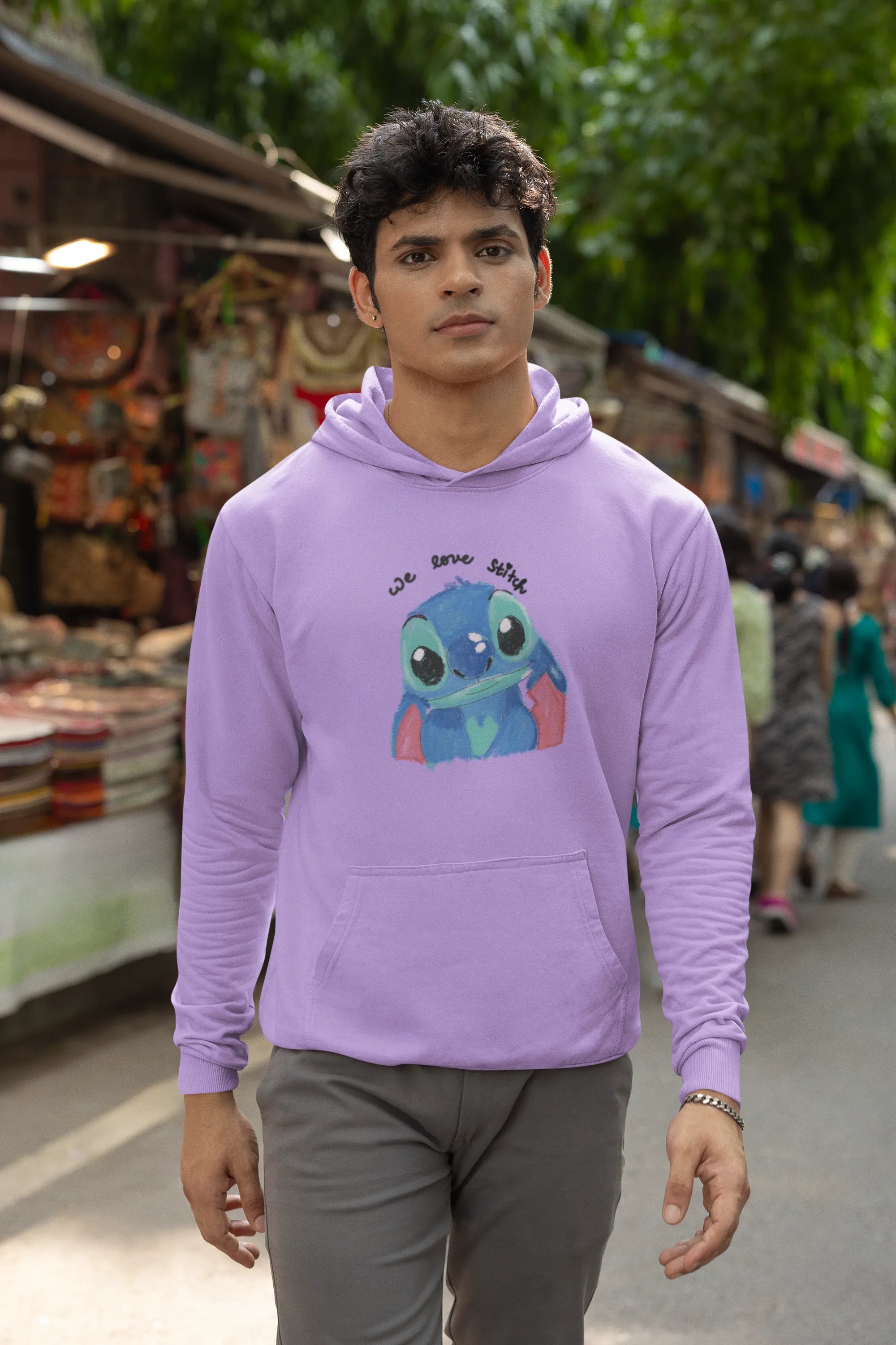 Fourth front view of a male model wearing a lavender hoodie with a large Stitch design. The illustration shows Stitch smiling and waving.