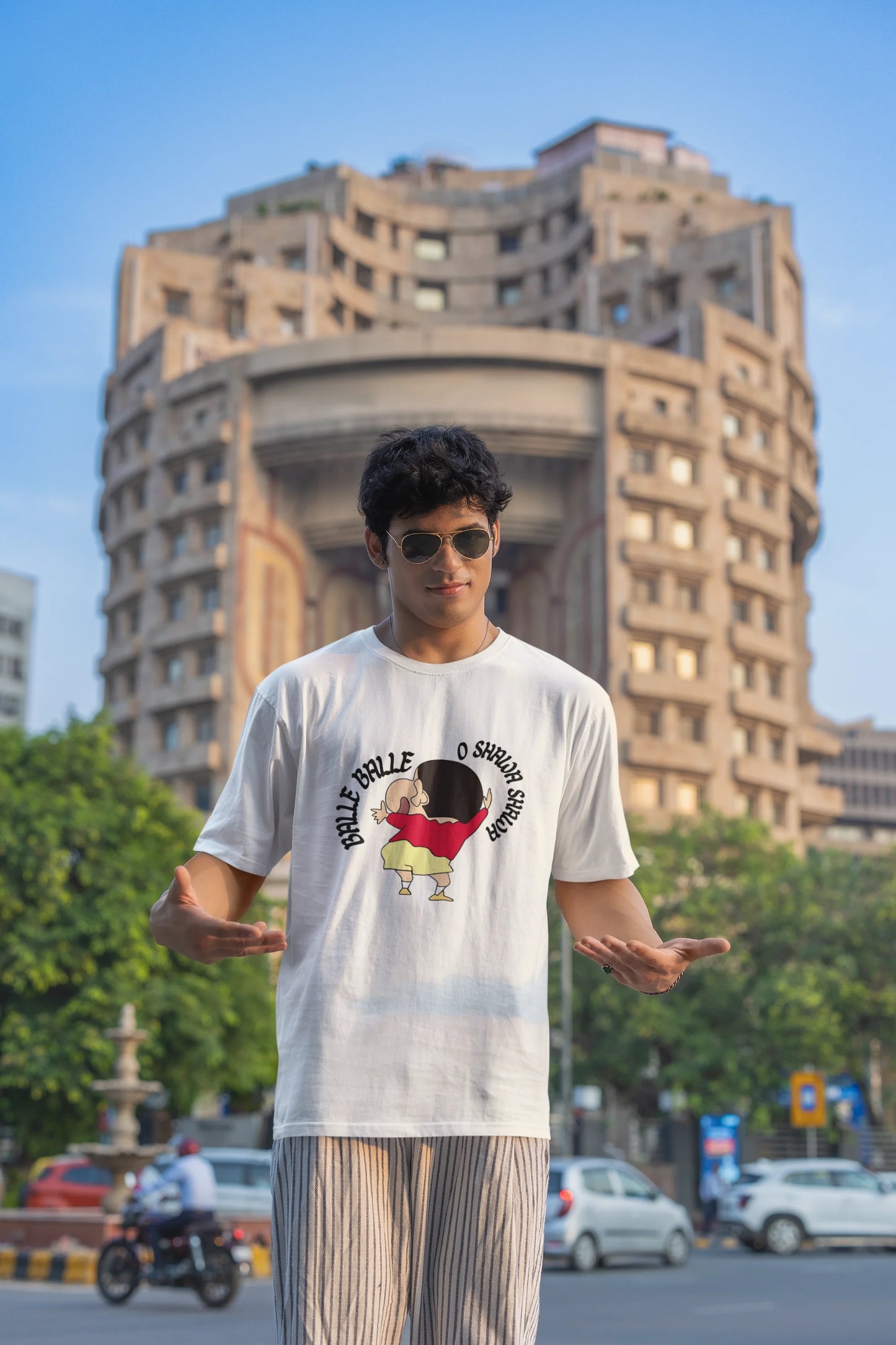 Third front view of male model wearing an oversized off-white tee with Shinchan dancing and the text "Balle Balle". A perfect blend of anime and Bollywood for Shinchan fans.