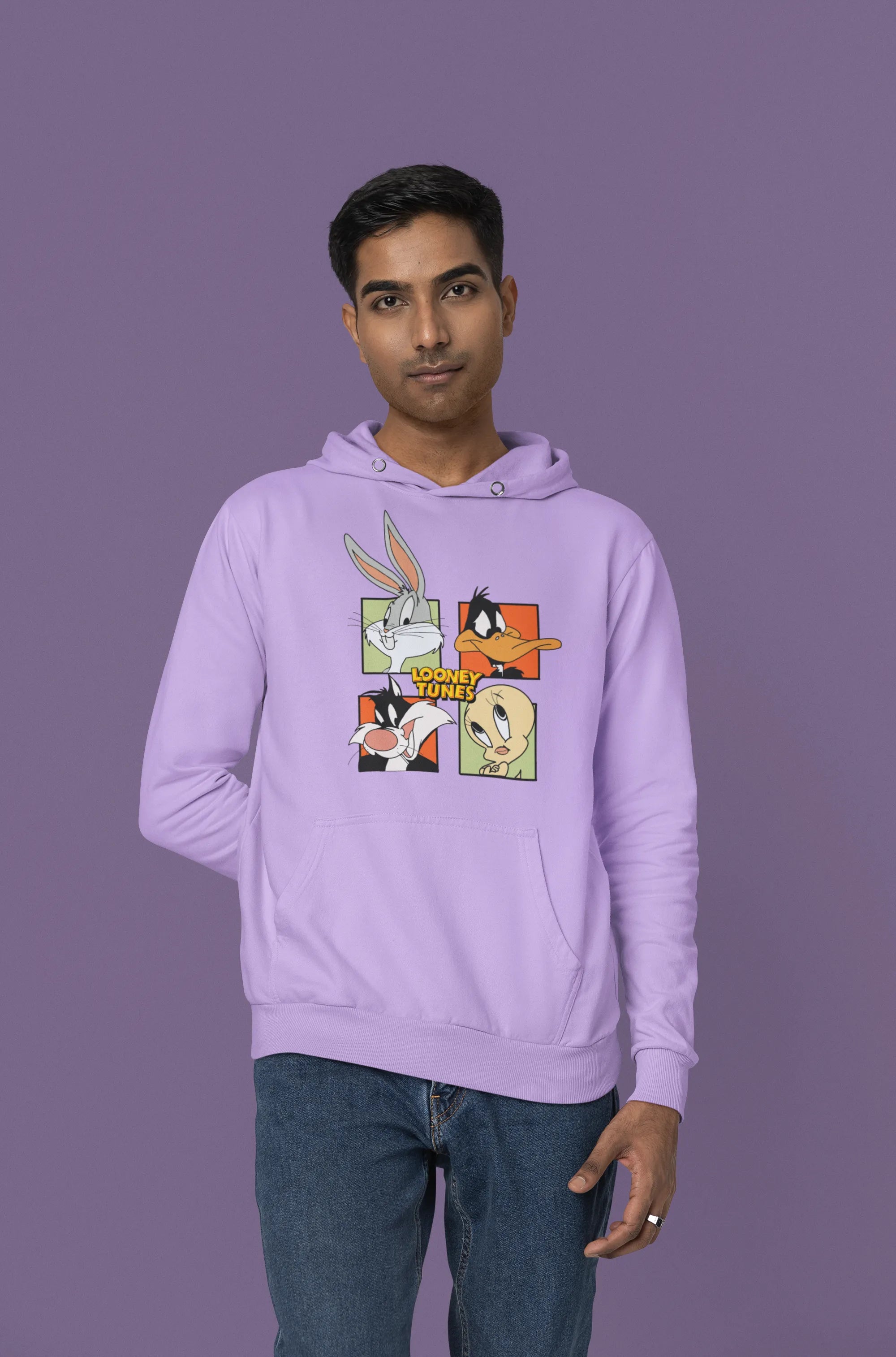 Fourth image of a male model wearing a lavender hoodie with a large Looney Tunes design. The illustration features portraits of several iconic Looney Tunes characters.