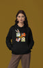 First image of a female model wearing a black hoodie with a large Looney Tunes design. The illustration features portraits of several iconic Looney Tunes characters.