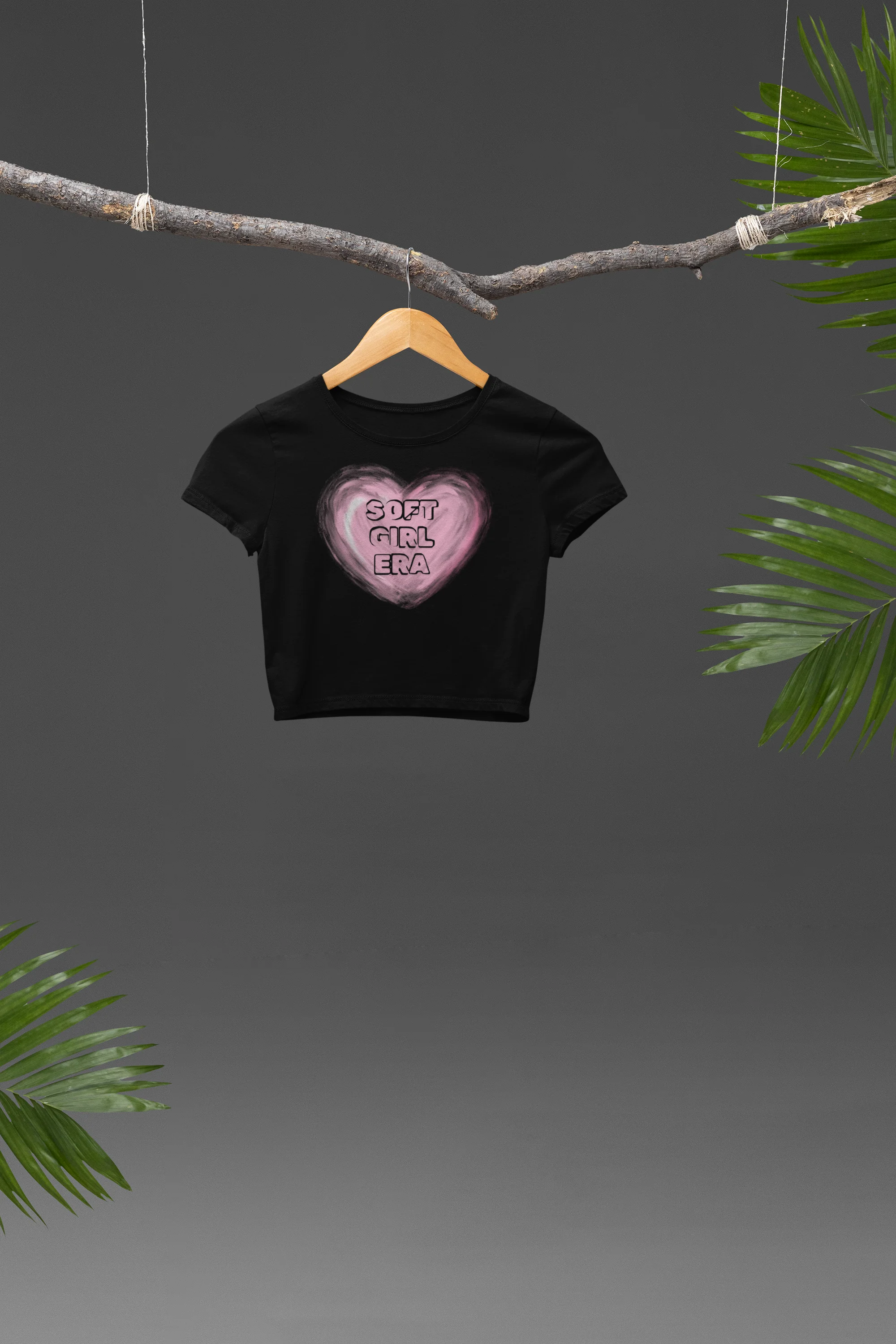 Front view of a black crop top with a heart-shaped "soft girl era" design, embodying the soft girl aesthetic.