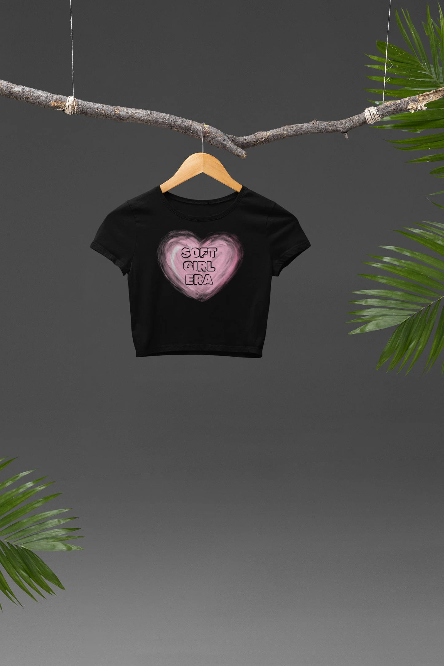 Front view of a black crop top with a heart-shaped "soft girl era" design, embodying the soft girl aesthetic.