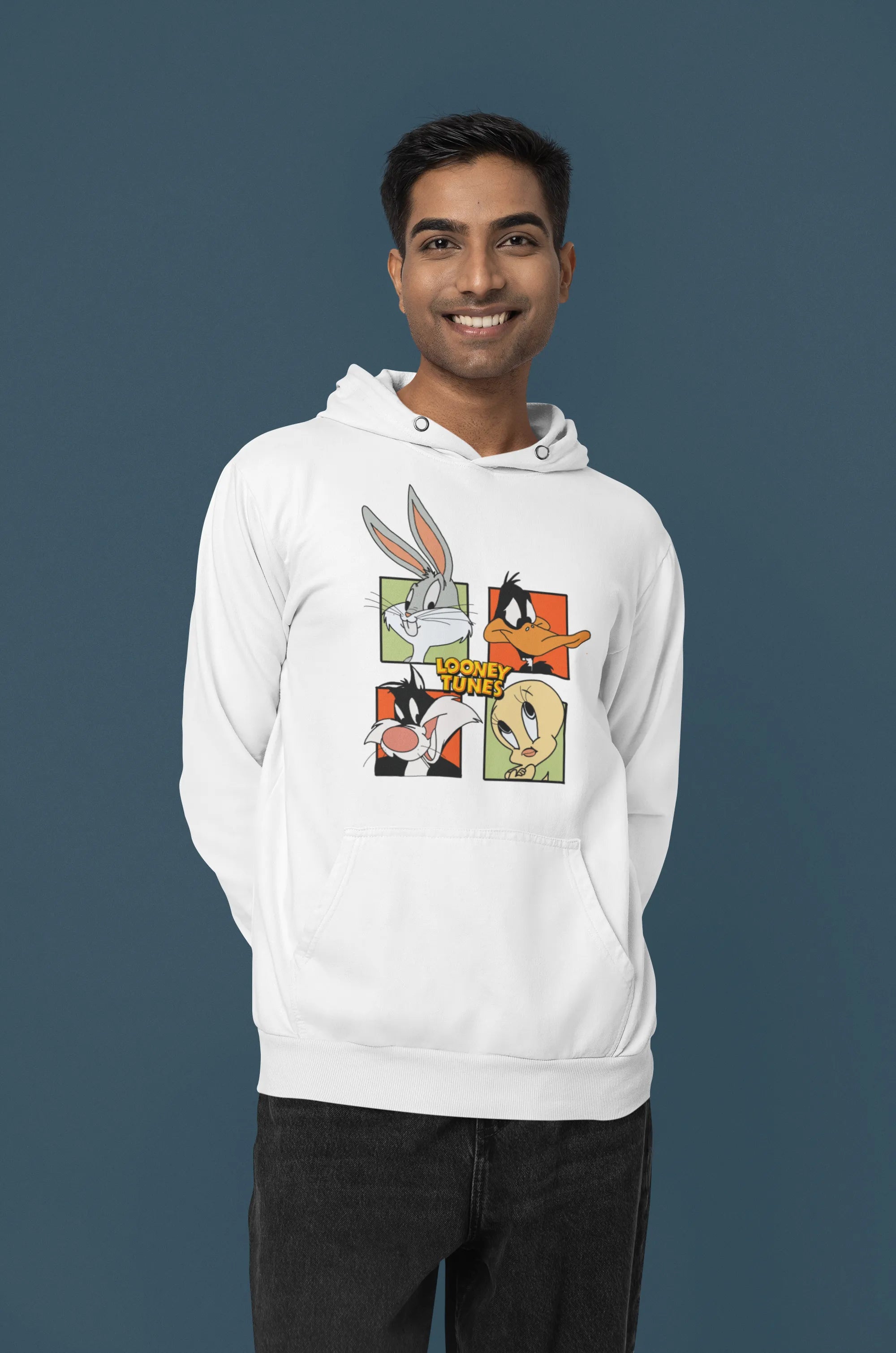 Third image of a male model wearing a white hoodie with a large Looney Tunes design. The illustration features portraits of several iconic Looney Tunes characters.