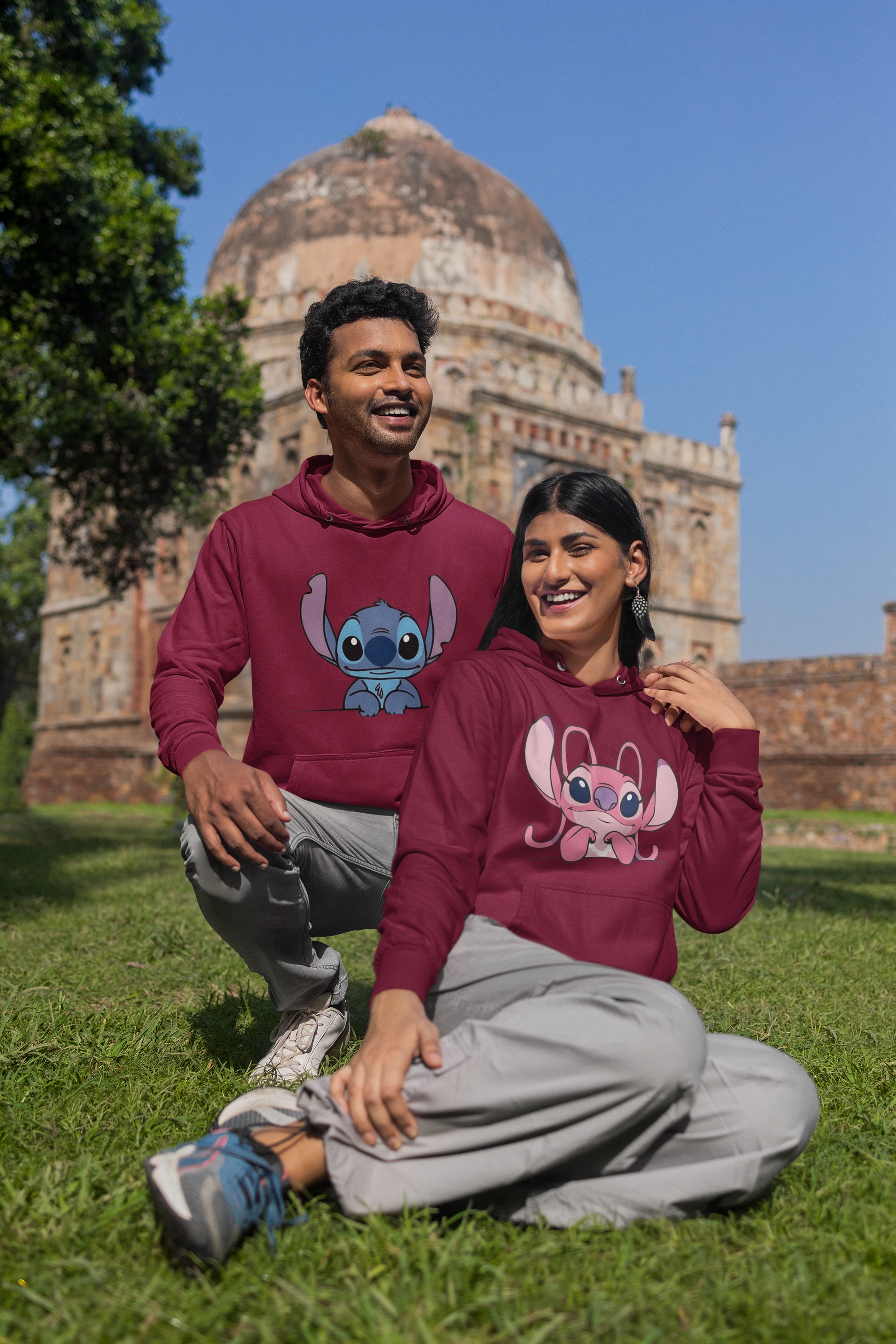 First front view of a couple wearing matching maroon hoodies, one with a Stitch design and the other with an Angel design.