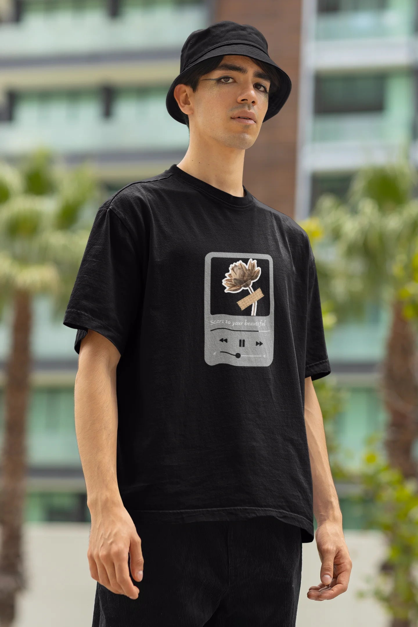 Left side view of a male model wearing a black oversized t-shirt featuring a design inspired by Alessia Cara's song "Scars to Your Beautiful." The design includes flowers and a message of self-love. Ideal for fans of Alessia Cara and those who appreciate messages of empowerment.