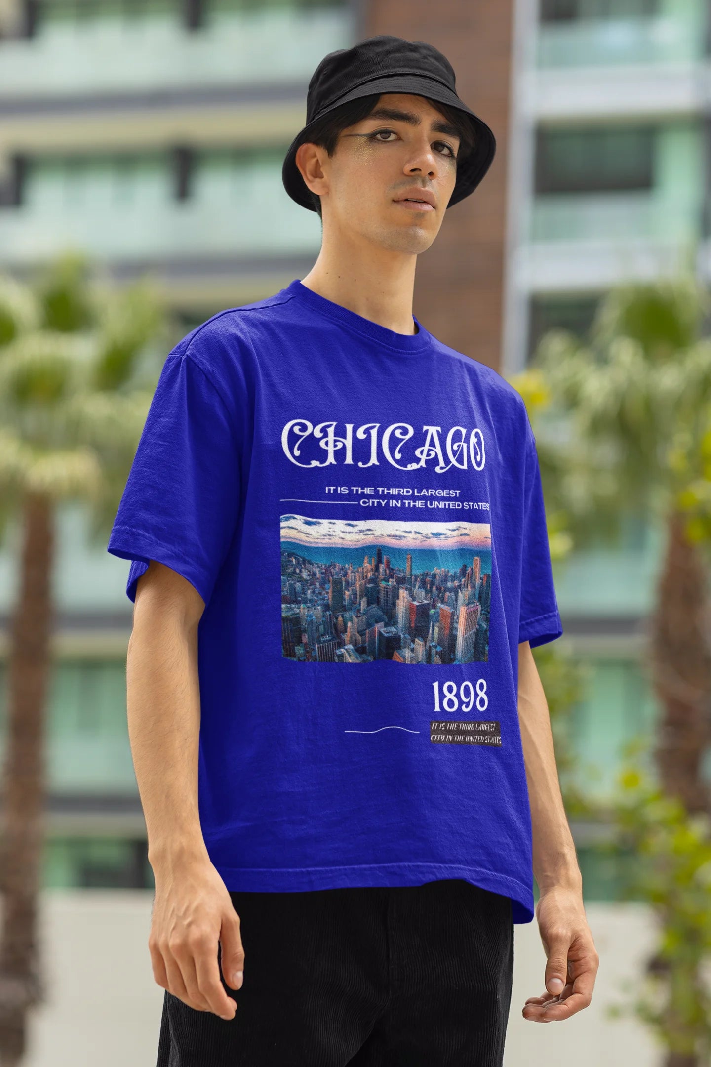 Left side view of male model wearing a royal blue oversized t-shirt with a Chicago skyline design, offering a relaxed urban aesthetic.
