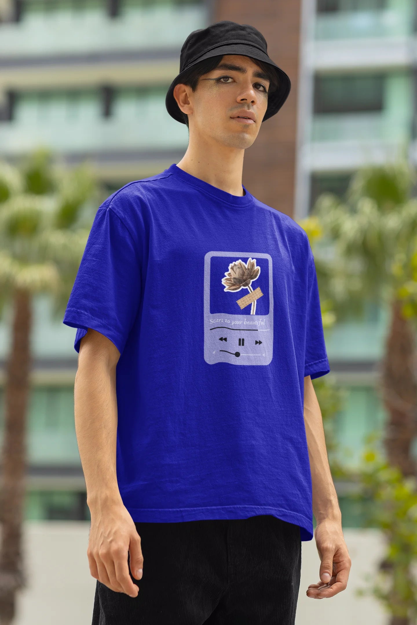 Right side view of a male model wearing a royal blue oversized t-shirt featuring a design inspired by Alessia Cara's song "Scars to Your Beautiful." The design includes flowers and a message of self-love. Ideal for fans of Alessia Cara and those who appreciate messages of empowerment.