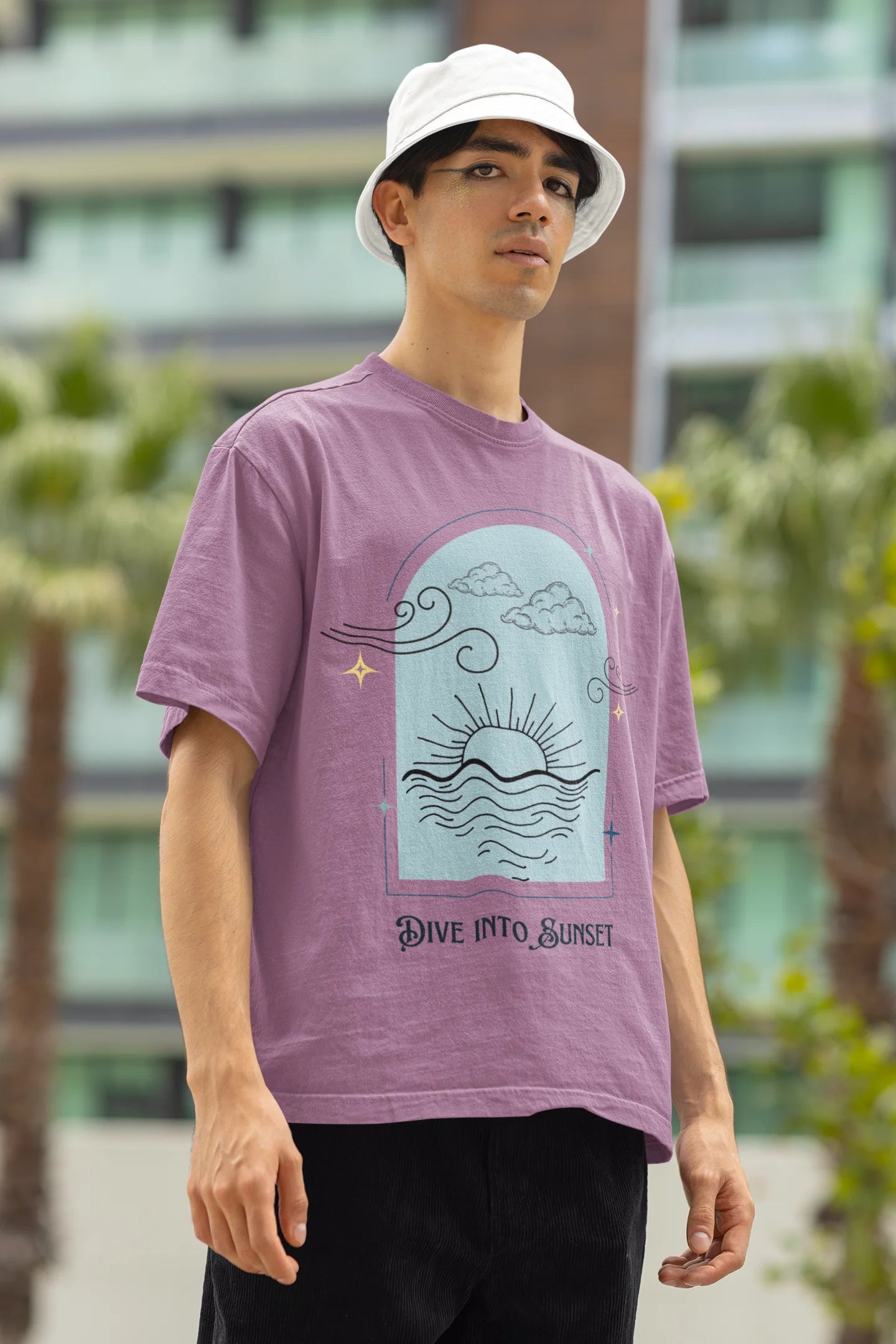 Right side view of a male model wearing a dirty purple oversized t-shirt with a beautiful outline of the sun setting into the sea, offering a serene and coastal aesthetic.