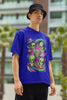 Right side view of a male model wearing a royal blue oversized t-shirt with a psychedelic design featuring green aliens and spaceships, perfect for a hippie, trance, or groovy style.