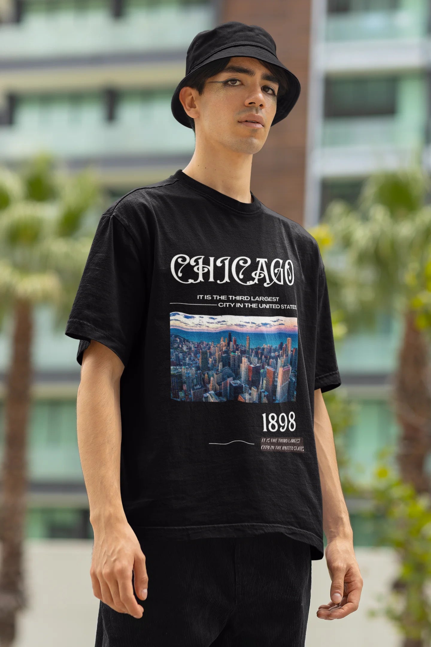 Left side view of male model wearing a black oversized t-shirt with a Chicago skyline design, offering a relaxed urban aesthetic.