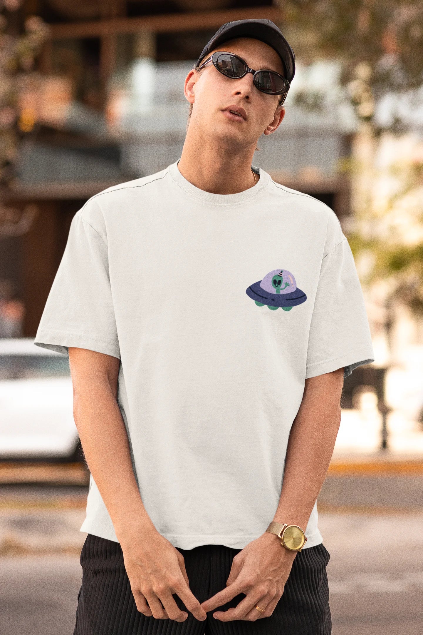 First front view of a male model wearing a off-white oversized t-shirt featuring a fun "Alienated" design with elements of spaceships, UFOs, and a hint of extraterrestrial life.