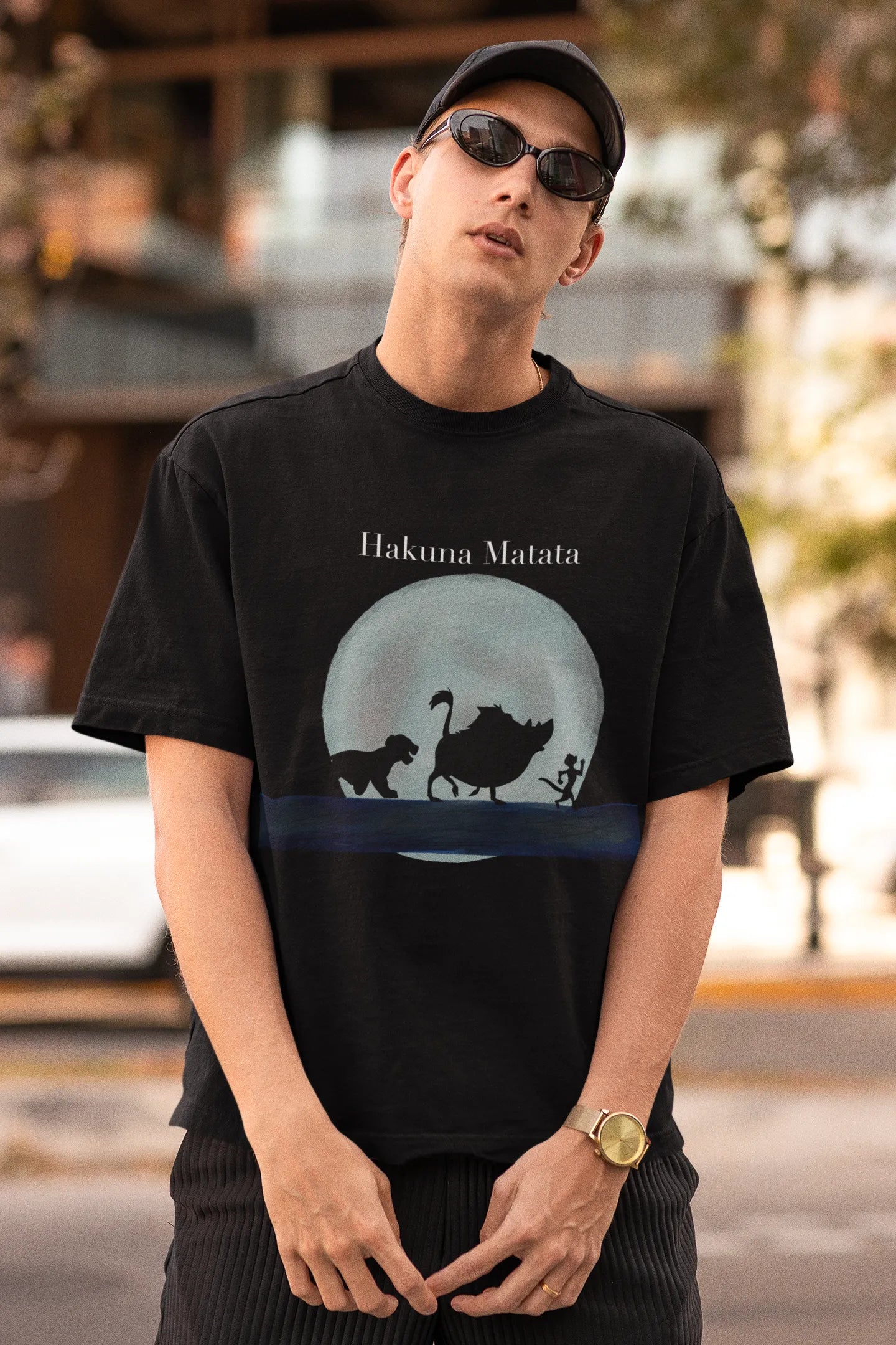 First image of male model showcasing black oversized t-shirts inspired by Hakuna Matata from Disney's Lion King, featuring Pumbaa, Simba and other iconic characters.