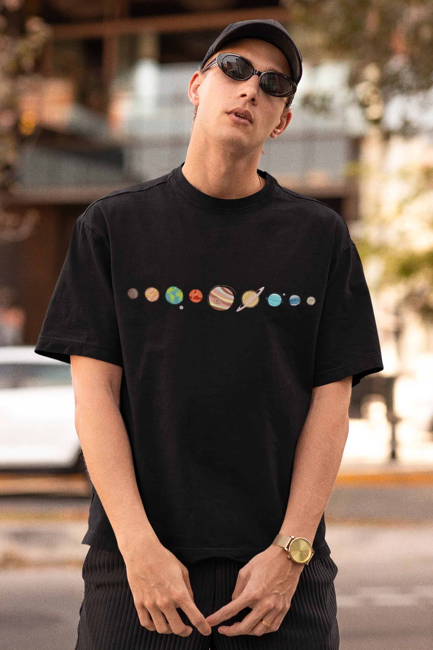 Front view of male model wearing an black oversized t-shirt featuring a colorful "Solar System" design with all eight planets.
