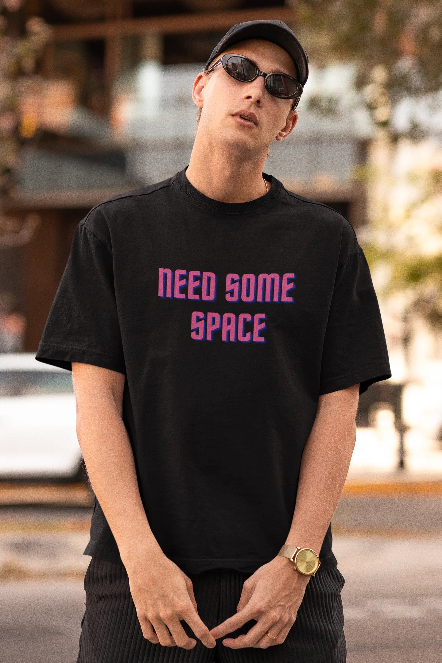 First front view image of a male model wearing a black oversized t-shirt with a bold graphic that reads "Need Some Space" on the front. The design incorporates subtle hints of the Milky Way galaxy and the solar system on the back.