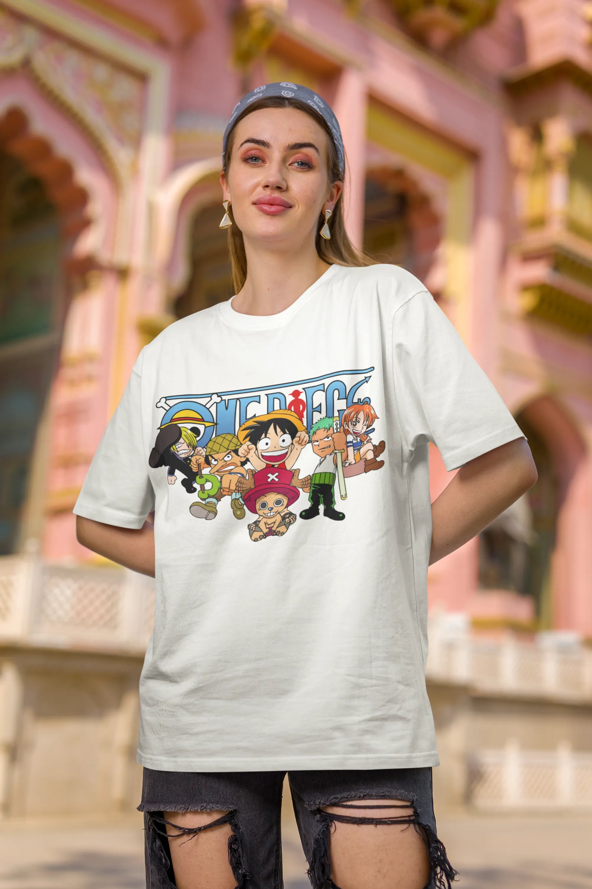 First front view of a female model wearing an off-white oversized t-shirt featuring chibi versions of the Straw Hat Crew from the One Piece anime.