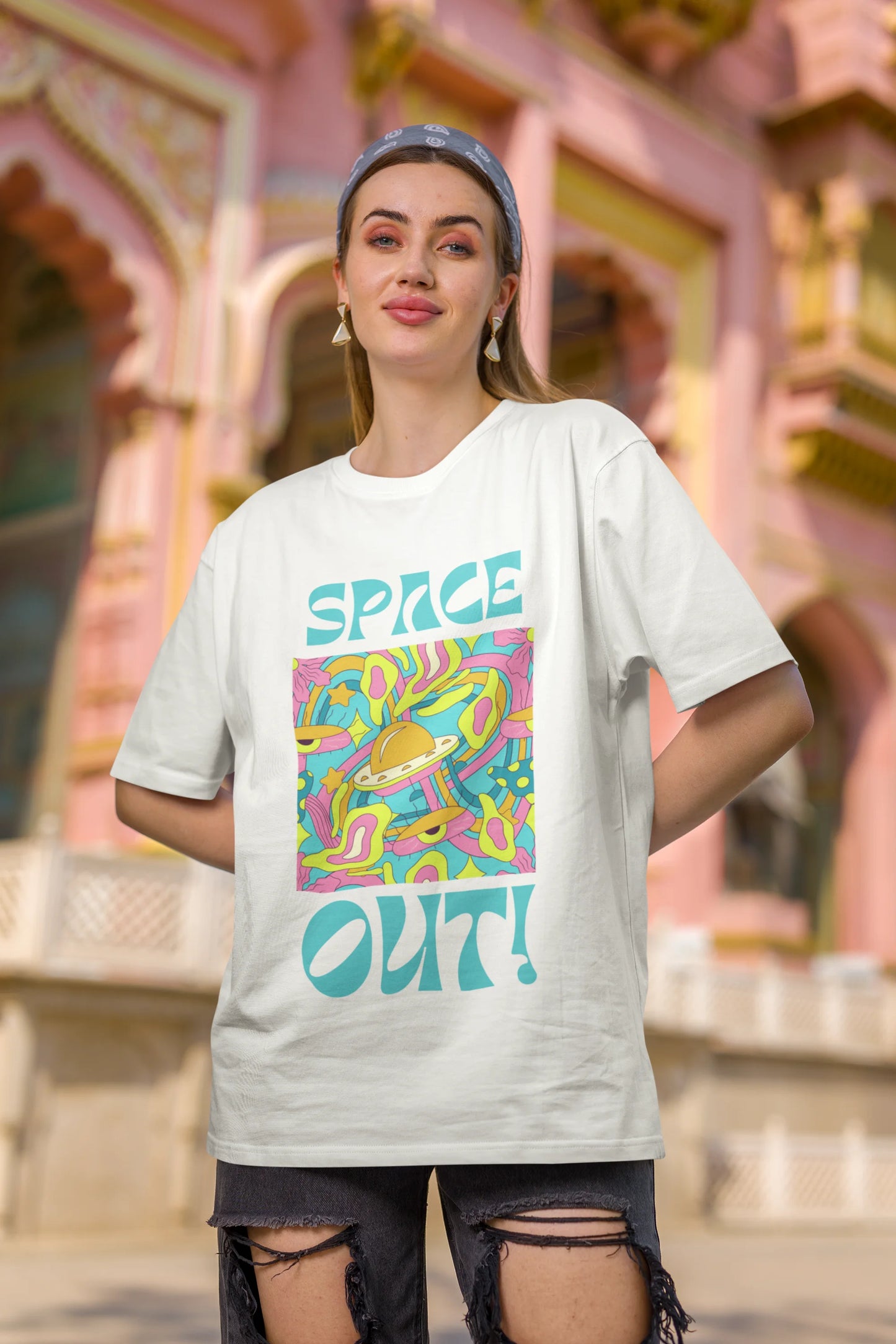 Second image of female model wearing an off white oversized "Spaced Out" t-shirt featuring a vibrant color mashup design that evokes a sense of space exploration, playful aliens, and distant galaxies.