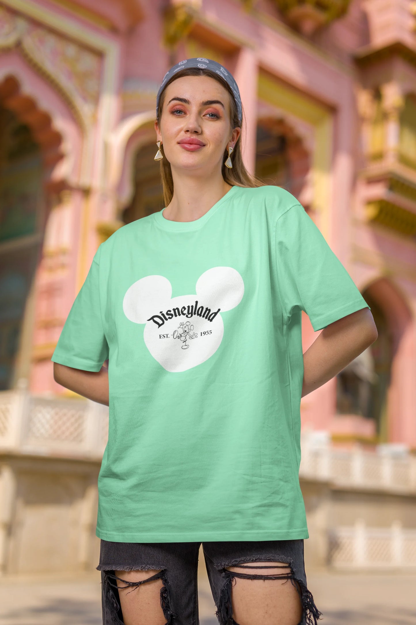 Second image of female model wearing a mint green oversized Disney collection t-shirt featuring a classic Disneyland design.