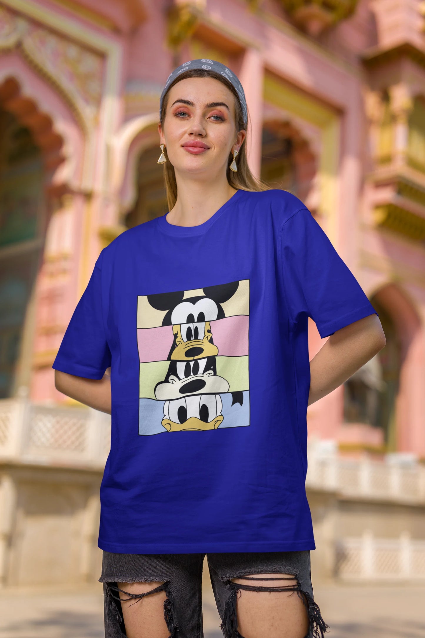 First image of female Models showcasing blue oversized t-shirt inspired by Mickey Mouse Clubhouse characters: Mickey Mouse, Donald Duck, Goofy, and Minnie Mouse