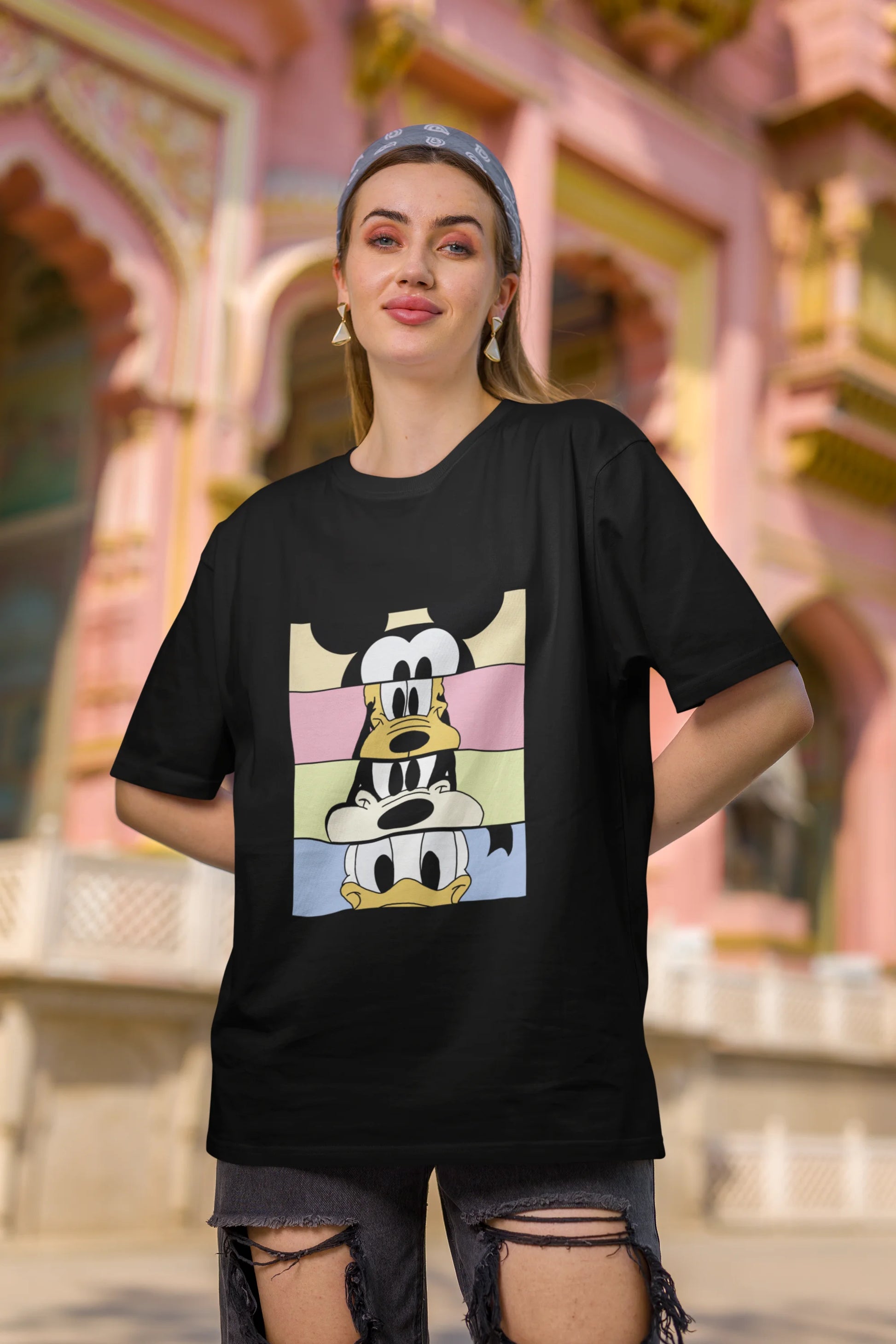 First image of female Model showcasing black oversized t-shirt inspired by Mickey Mouse Clubhouse characters: Mickey Mouse, Donald Duck, Goofy, and Minnie Mouse