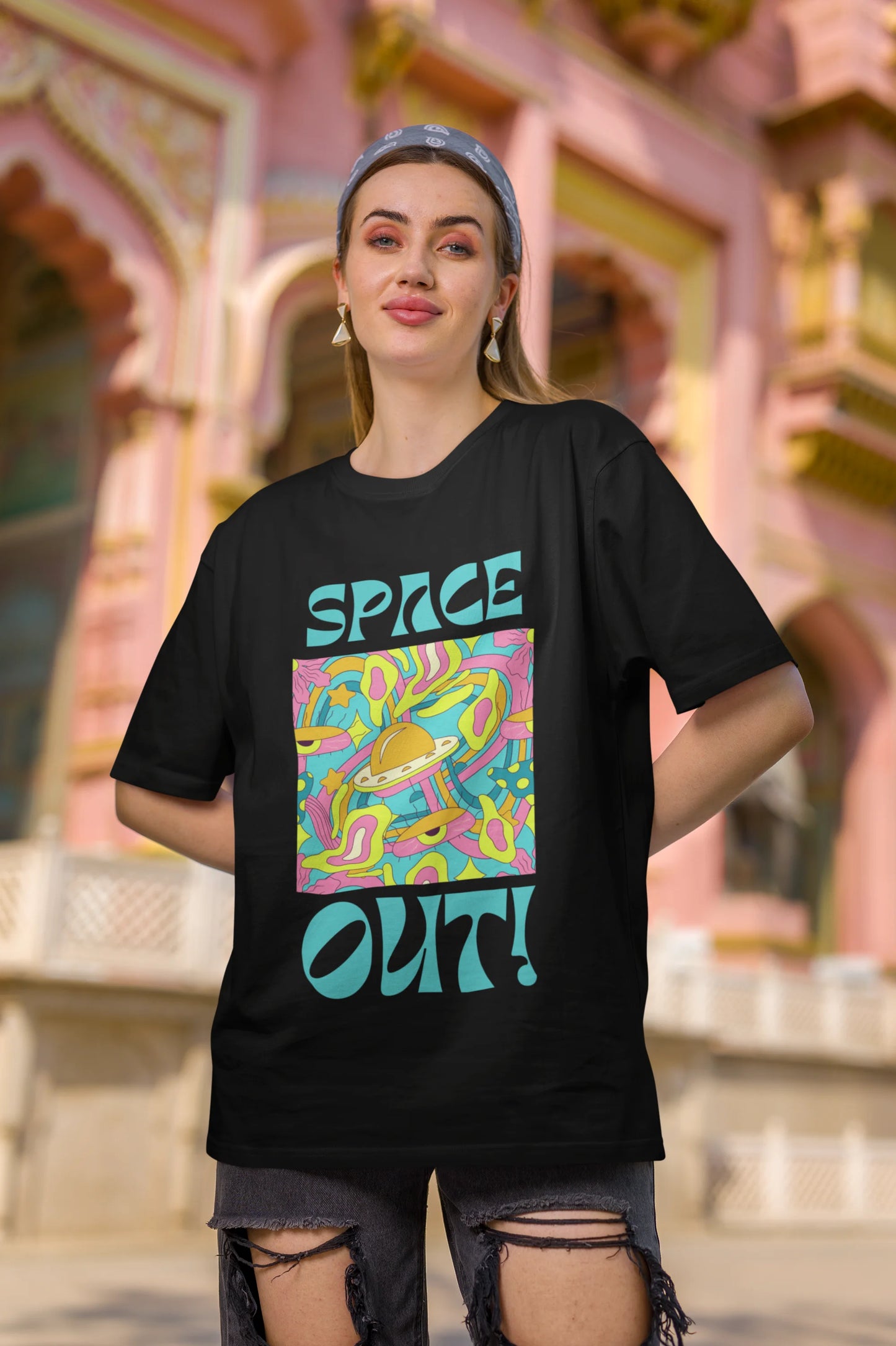 Second image of female model wearing an black oversized "Spaced Out" t-shirt featuring a vibrant color mashup design that evokes a sense of space exploration, playful aliens, and distant galaxies.