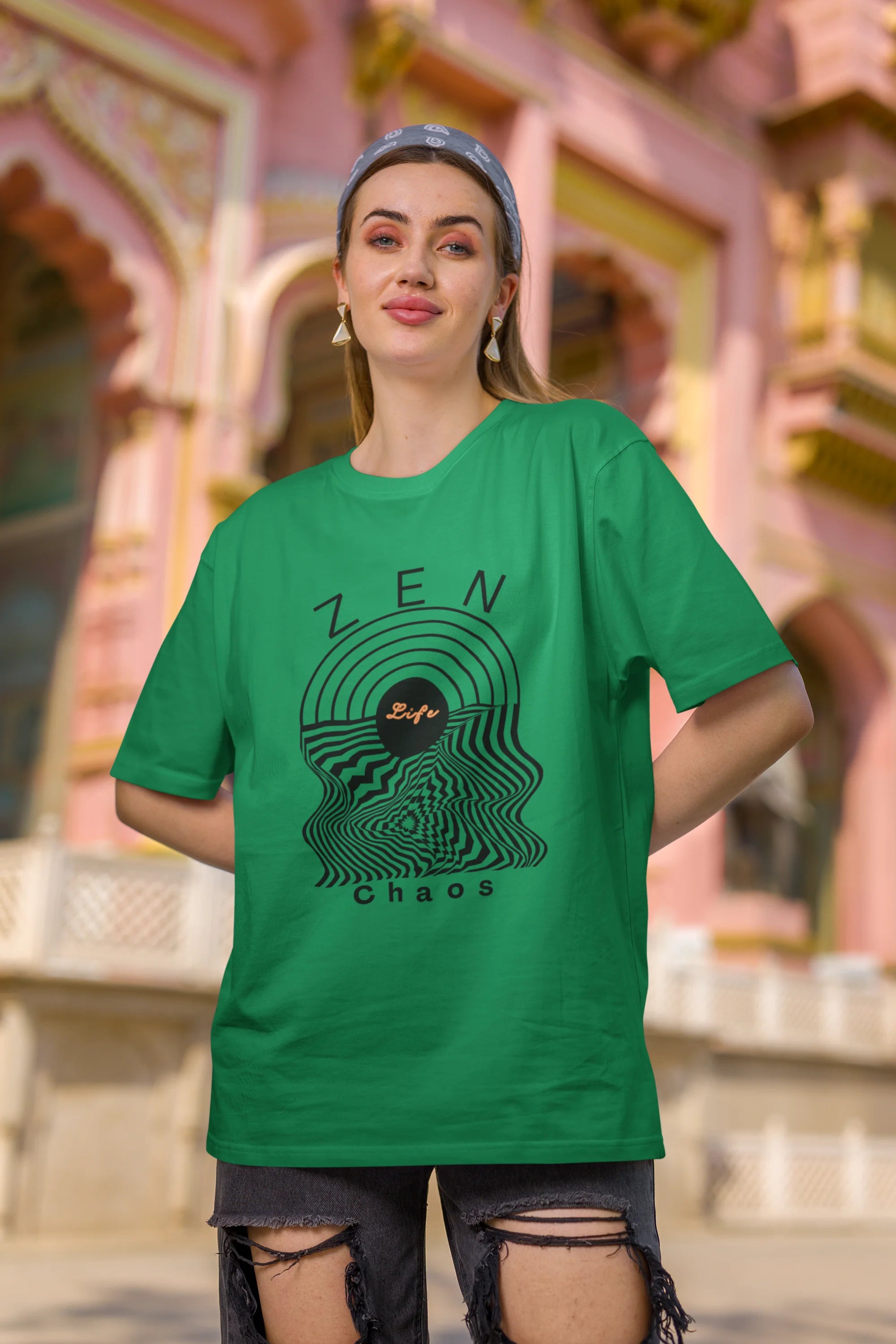 Second front view of a female model wearing an forest green oversized t-shirt featuring an aesthetic design of a setting sun and crashing waves with the text "Zen & Chaos" above it. Ideal for those who love philosophical themes and visually striking clothing.