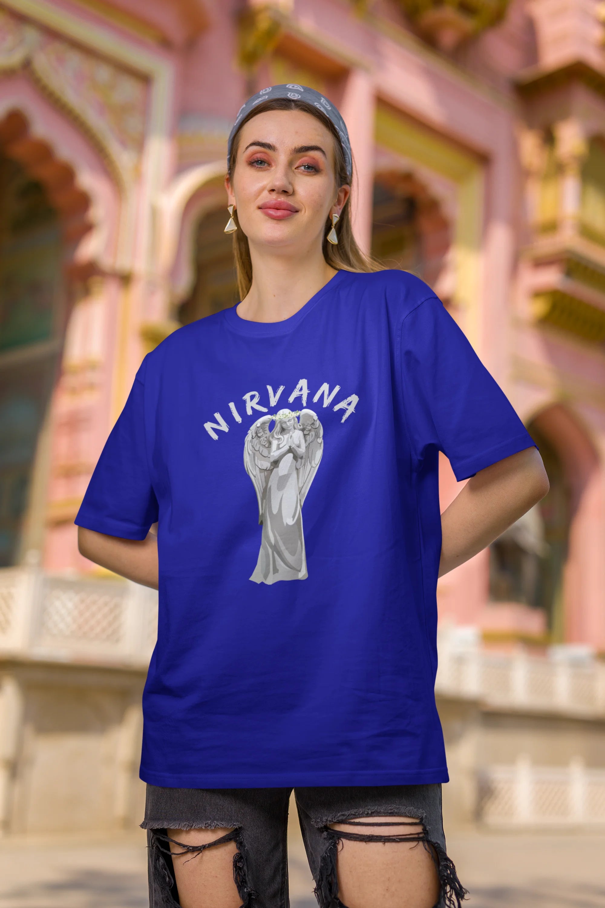 First front image of female model wearing a\ royal blue oversized t-shirt featuring a design of a winged angel with the text "Nirvana" above it. Ideal for fans of Nirvana and those who love grunge aesthetics.