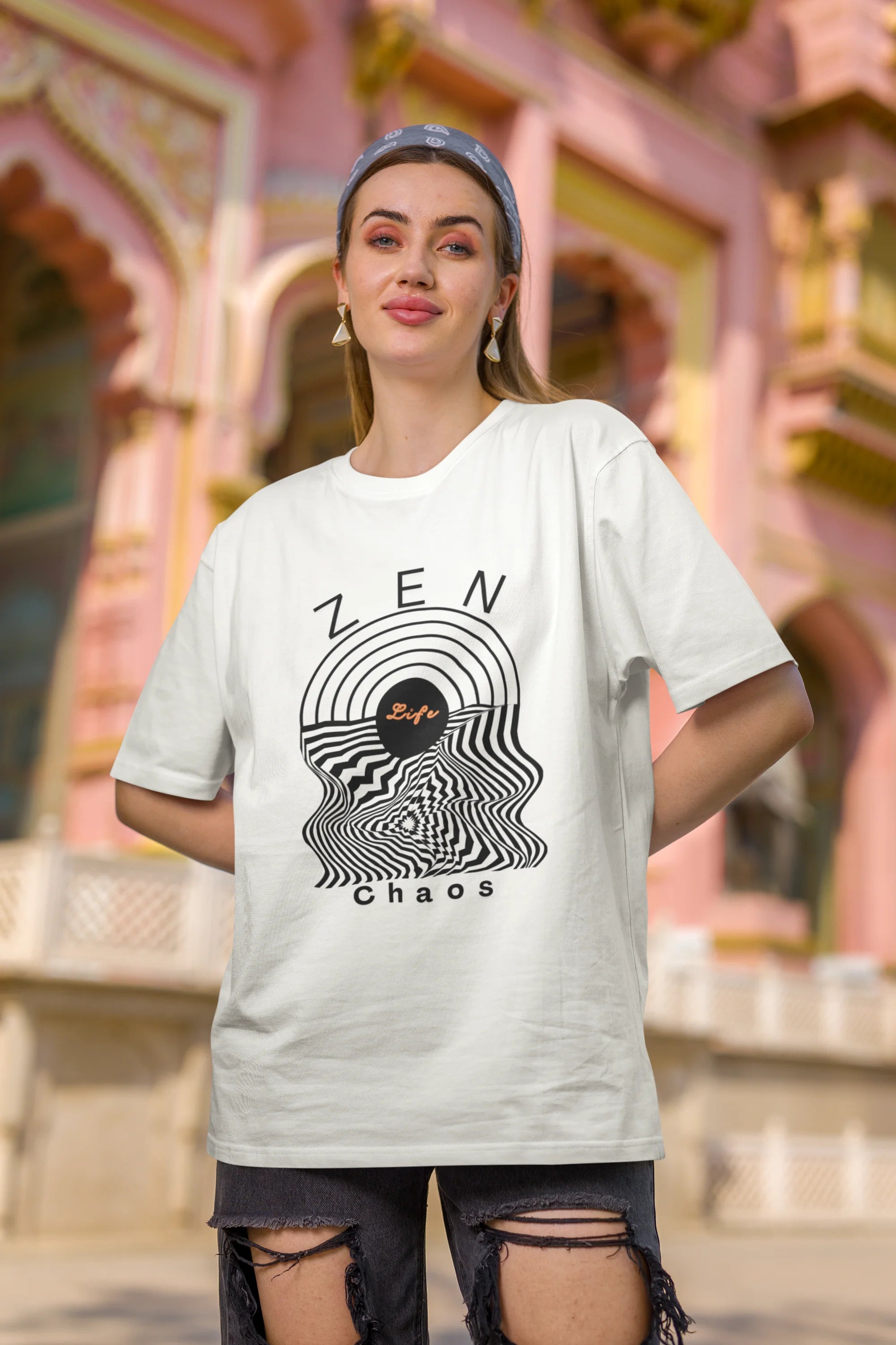 Second front image of a female model wearing an off-white oversized t-shirt featuring an aesthetic design of a setting sun and crashing waves with the text "Zen & Chaos" above it. Ideal for those who love philosophical themes and visually striking clothing.