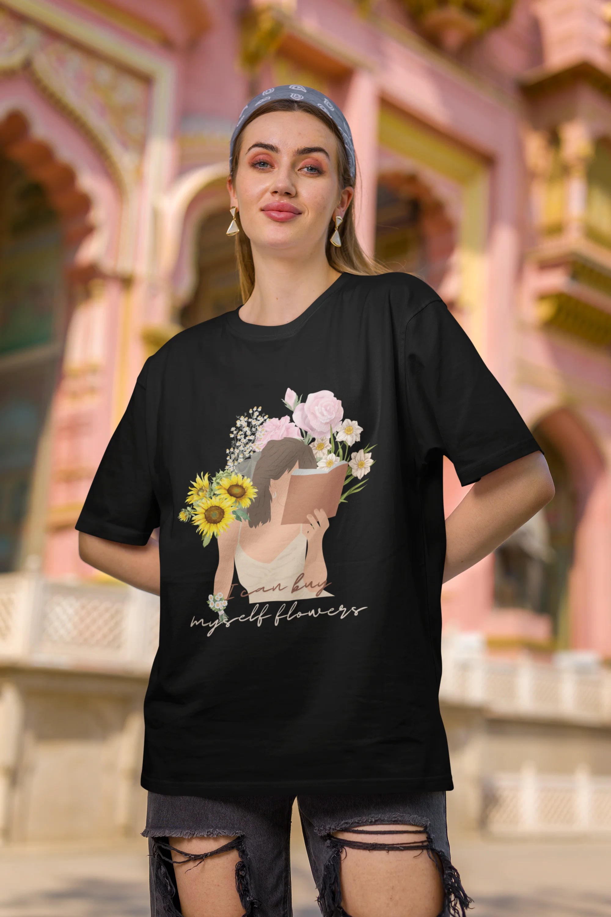 Second front view of female model wearing a black oversized t-shirt with a positive message "Buy Myself Flowers" and a graphic of a smiling woman surrounded by tulips and sunflowers. Ideal for those who love inspirational clothing and floral designs.