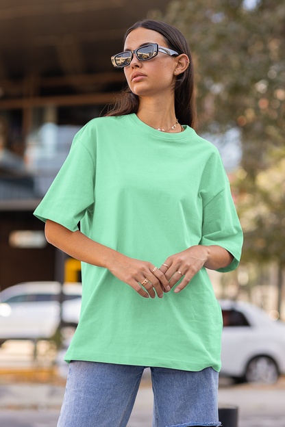First front view of a female model wearing a mint green oversized t-shirt featuring Crocodile, the Desiccation Master, from the One Piece anime.