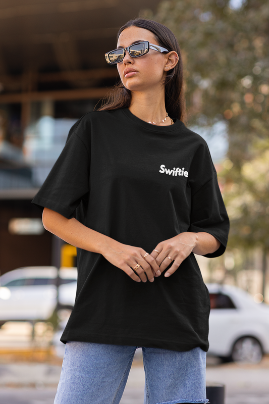 Side view of female model flaunting Taylor Swift-themed black oversized tee, epitomizing rockstar chic with nods to Taylor's Version and Eras Tour.