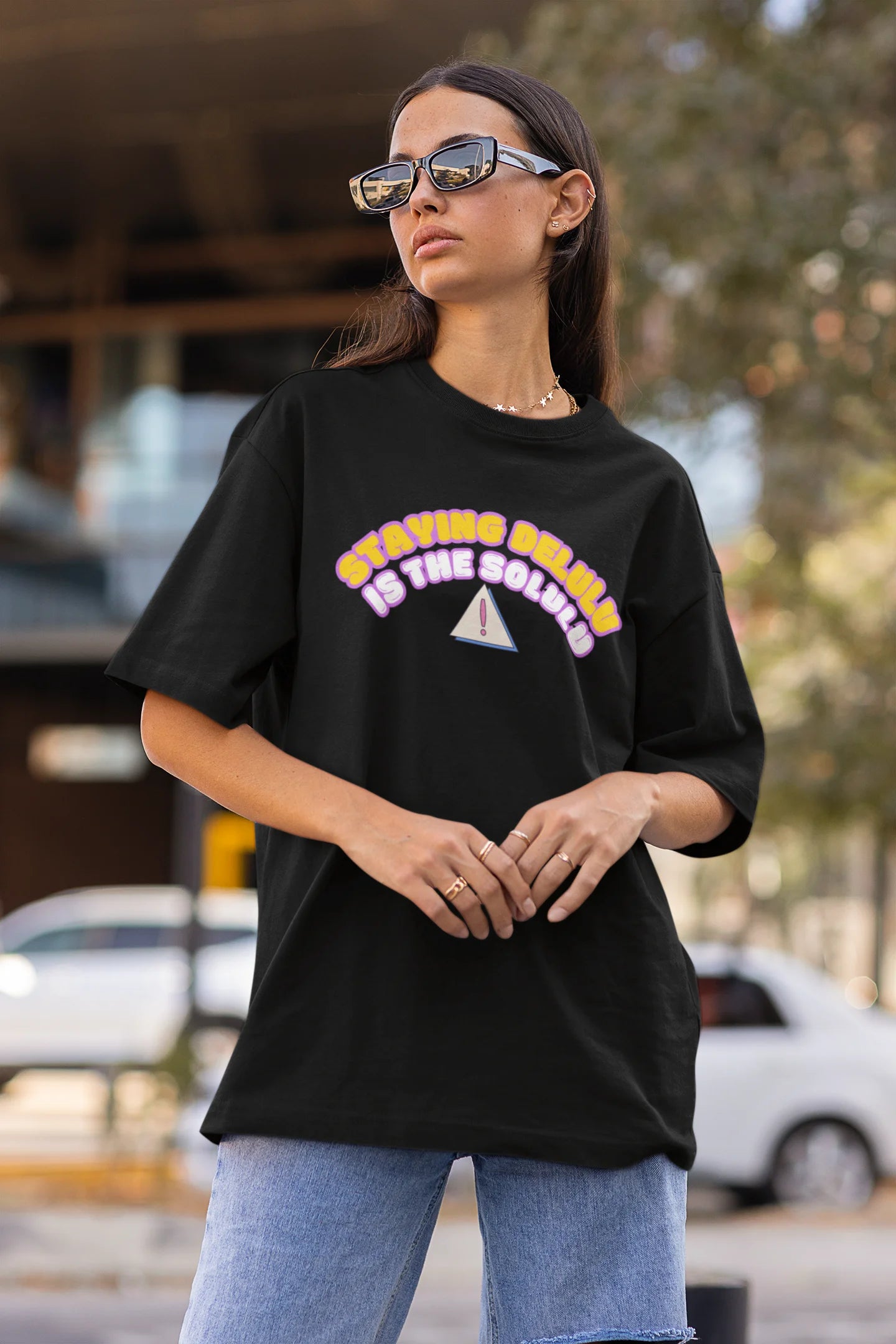 Side view of female model wearing a black oversized t-shirt with the hilarious message "Stay Delulu" in a bold design. Ideal for those who love trendy slang and lighthearted humor. 