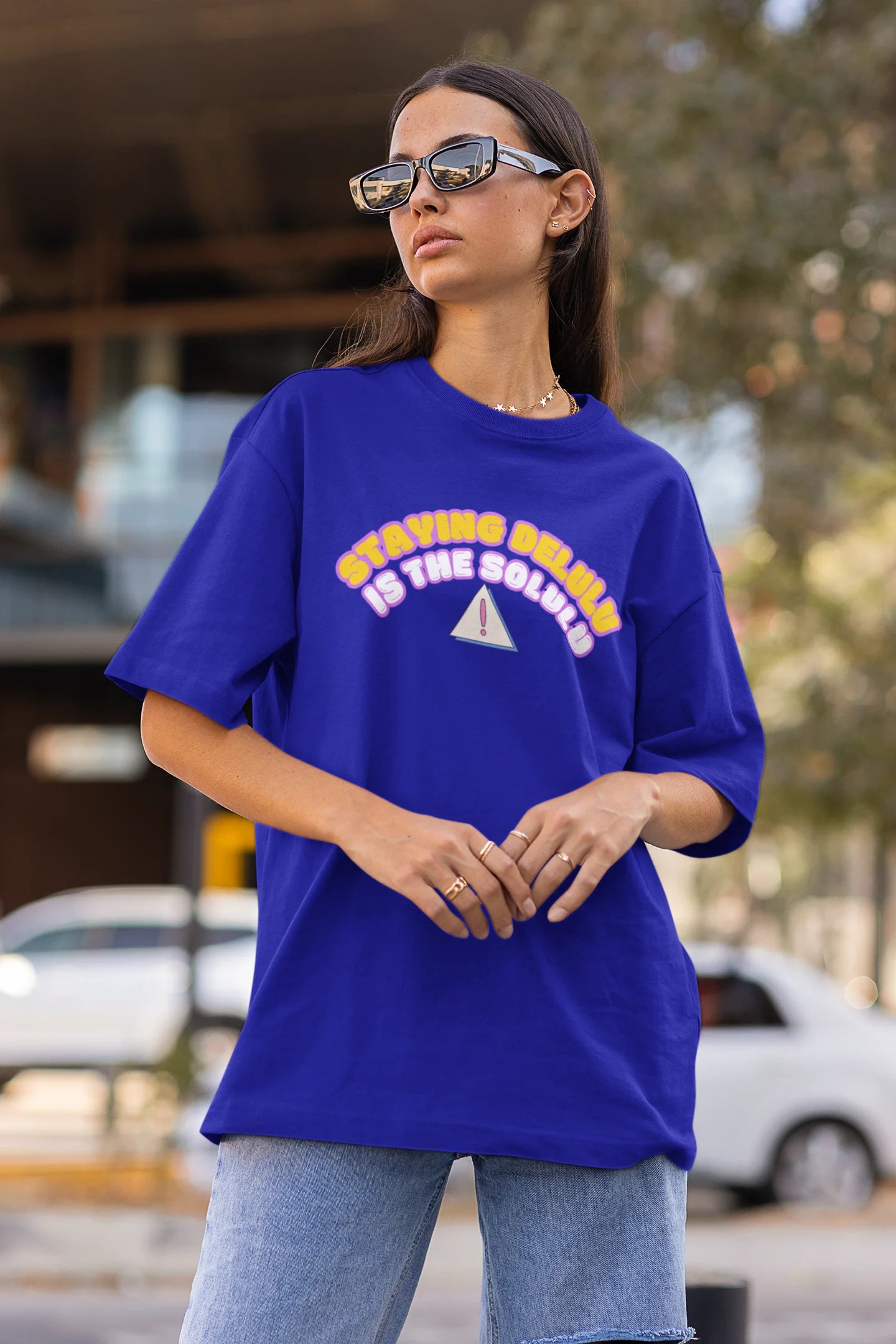 Side view of female model wearing an royal blue oversized t-shirt with the hilarious message "Stay Delulu" in a bold design. Ideal for those who love trendy slang and lighthearted humor. 