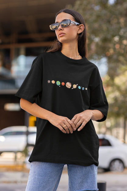Front view of female model wearing an black oversized t-shirt featuring a colorful "Solar System" design with all eight planets.