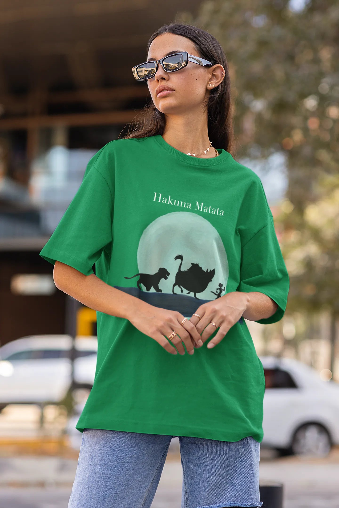 Side view of female model showcasing forest green oversized t-shirts inspired by Hakuna Matata from Disney's Lion King, featuring Pumbaa, Simba and other iconic characters.