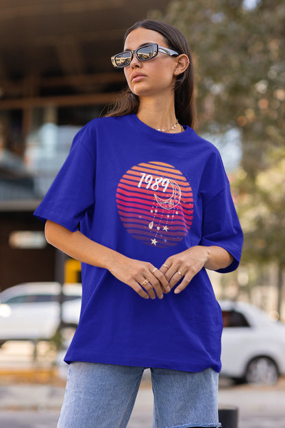 Side view of woman wearing blue coloured Oversize T-shirt featuring Taylor Swift 1989 design, Taylor's Version, and Eras Tour Merch