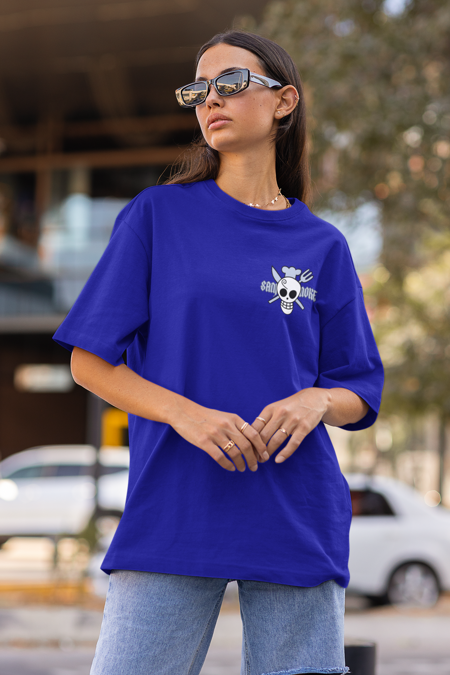 First front view of a female model wearing a royal blue oversized t-shirt featuring Sanji's skull and crossbones logo and the text "The Cook and Black Leg."