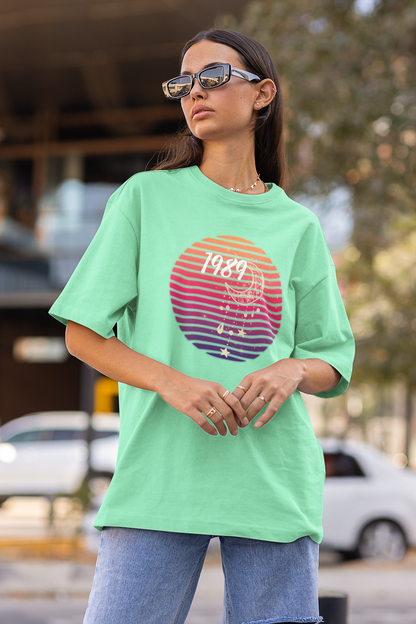 Side view of woman wearing mint green coloured Oversize T-shirt featuring Taylor Swift 1989 design, Taylor's Version, and Eras Tour Merch