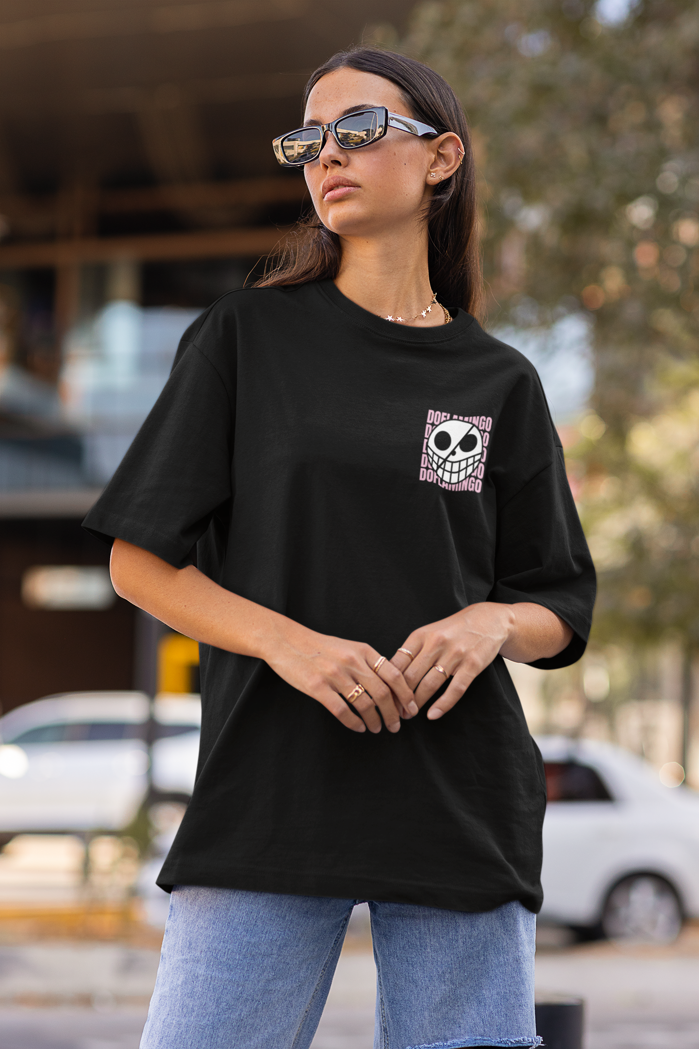 3rd front view of a female model wearing a black oversized t-shirt featuring Donquixote Doflamingo from the One Piece anime.
