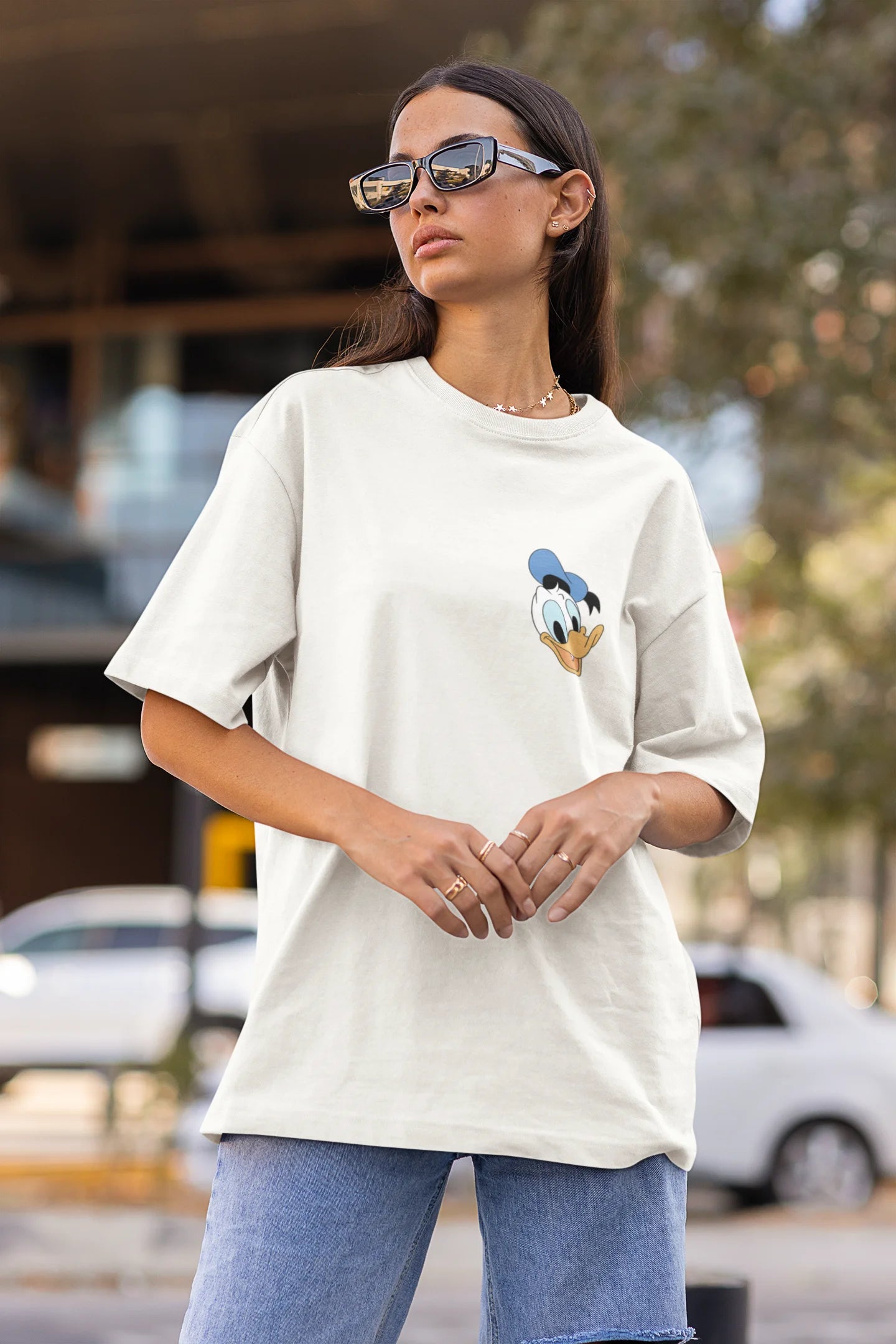 Side view of female model wearing off white oversized Disney collection t-shirt featuring a classic Donald Duck design.