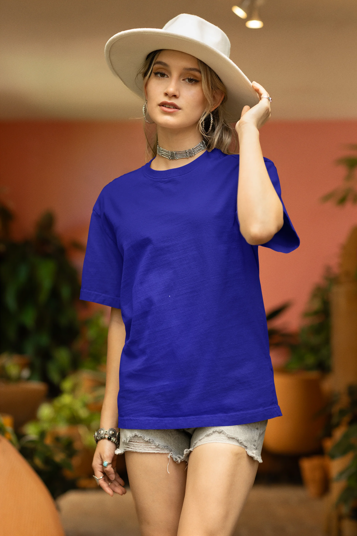 Front view of a female model wearing a royal blue oversized t-shirt featuring a beautiful rose design with inspirational text, offering a calming and uplifting aesthetic.