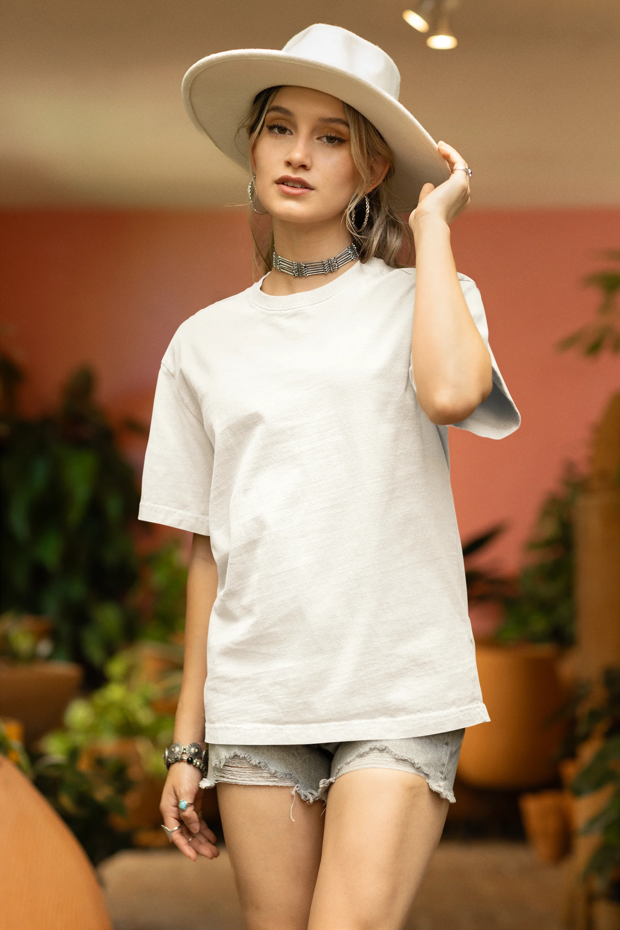 Front view of female model wearing an off-white oversized t-shirt featuring a thought-provoking design of a golden lock shaped like an insect. Ideal for those who love symbolic clothing and unique conversation starters.