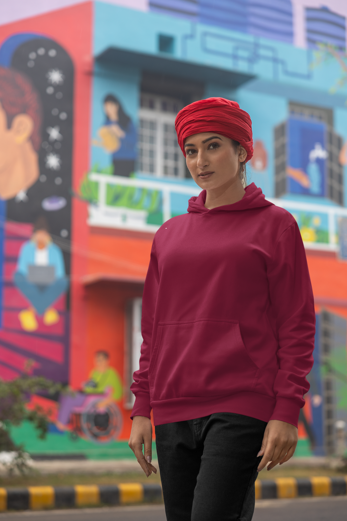 Second front view of a female model wearing a maroon hoodie with a portrait of Diljit Dosanjh and lyrics from the song "Ikk Kudi."