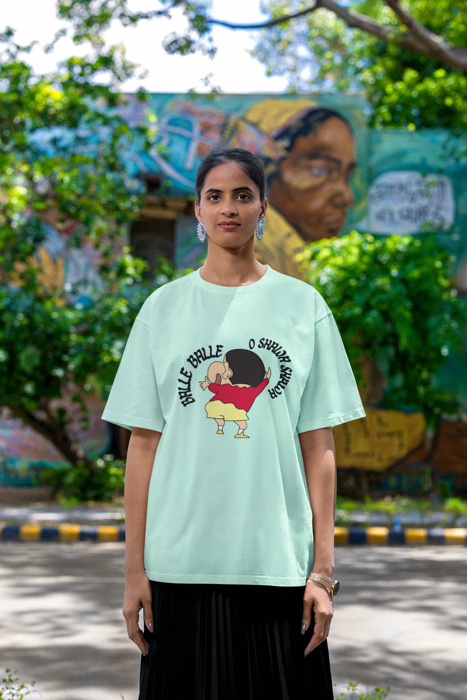 Fourth front view of female model wearing an oversized mint green tee with Shinchan dancing and the text "Balle Balle". A perfect blend of anime and Bollywood for Shinchan fans.
