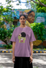 Second front view of female model wearing a dirty purple oversized t-shirt with a design of Shinchan laughing hysterically. Perfect for Shinchan fans who love the character's humor.