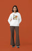 Fourth image of a female model wearing a white hoodie with a large Looney Tunes design. The illustration features portraits of several iconic Looney Tunes characters.