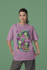 First front view of a female model wearing a dirty purple oversized t-shirt with a psychedelic design featuring green aliens and spaceships, perfect for a hippie, trance, or groovy style.