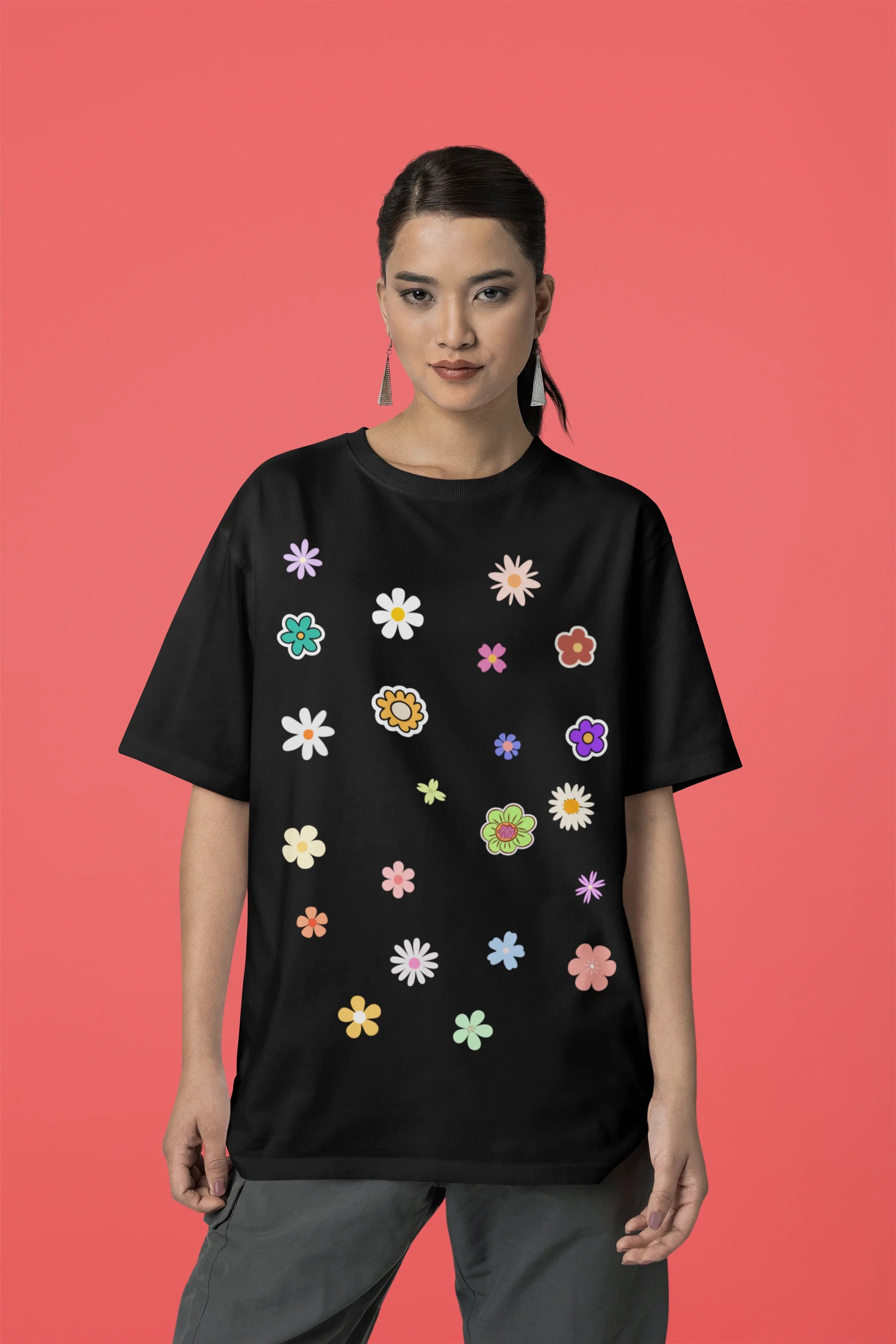 Front view of female model wearing a black oversized t-shirt featuring a vibrant floral design with roses, tulips, sunflowers, and orchids. Ideal for those who love floral patterns and spring fashion. 