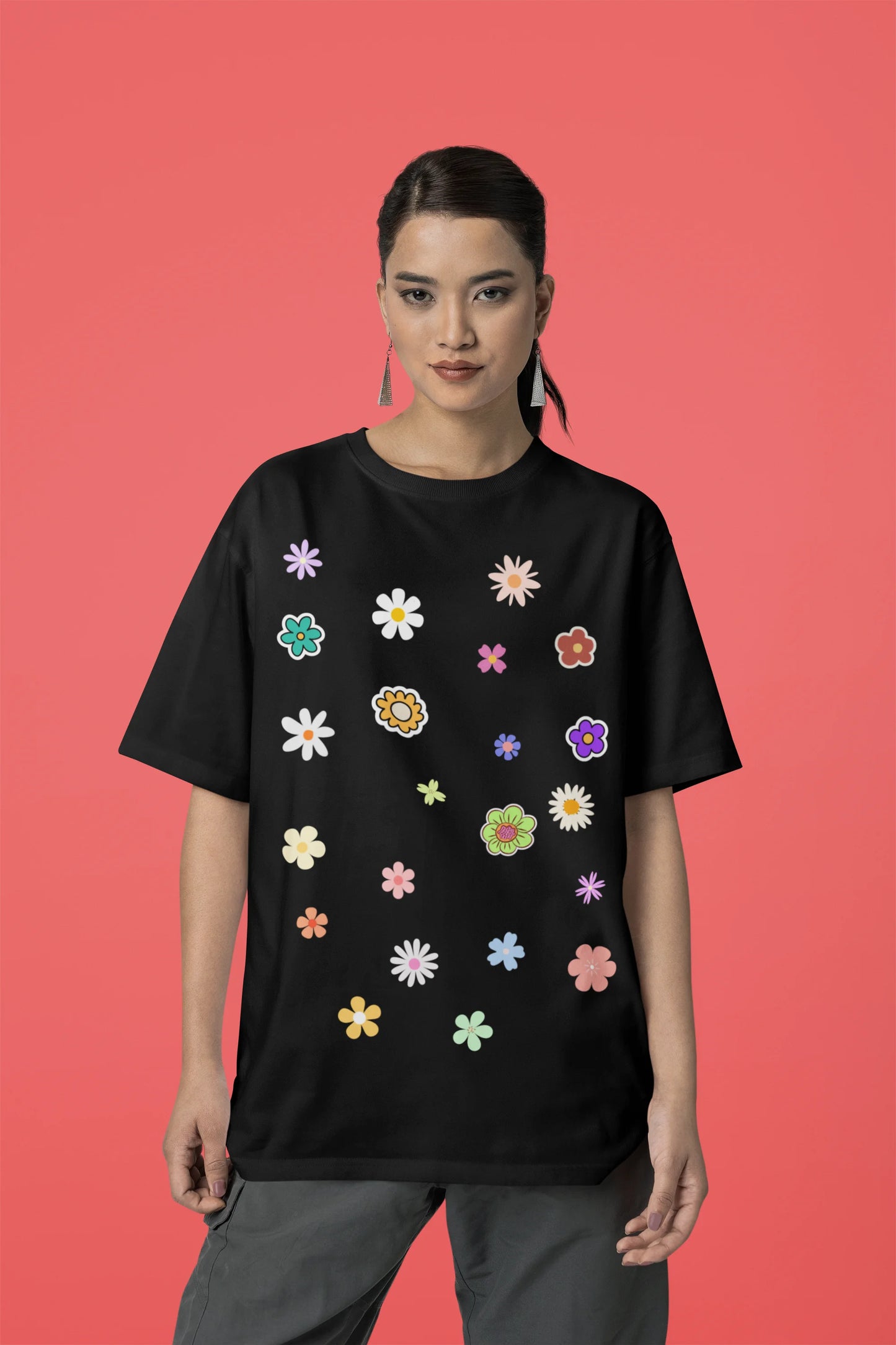 Front view of female model wearing a black oversized t-shirt featuring a vibrant floral design with roses, tulips, sunflowers, and orchids. Ideal for those who love floral patterns and spring fashion.