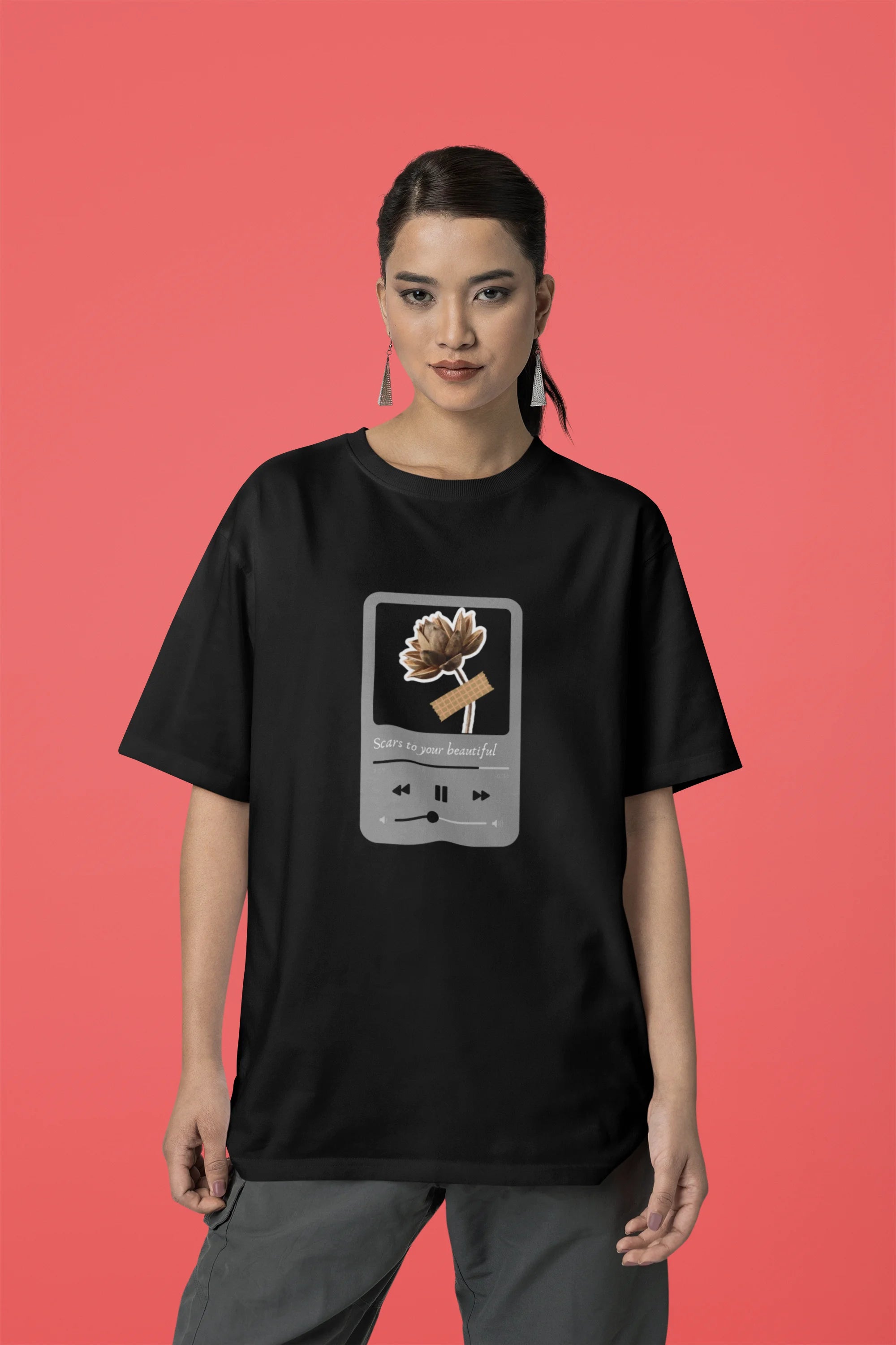 Third front view of a female model wearing a black oversized t-shirt featuring a design inspired by Alessia Cara's song "Scars to Your Beautiful." The design includes flowers and a message of self-love. Ideal for fans of Alessia Cara and those who appreciate messages of empowerment.