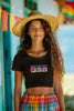 First front view of a female model wearing a black crop top with a floral 